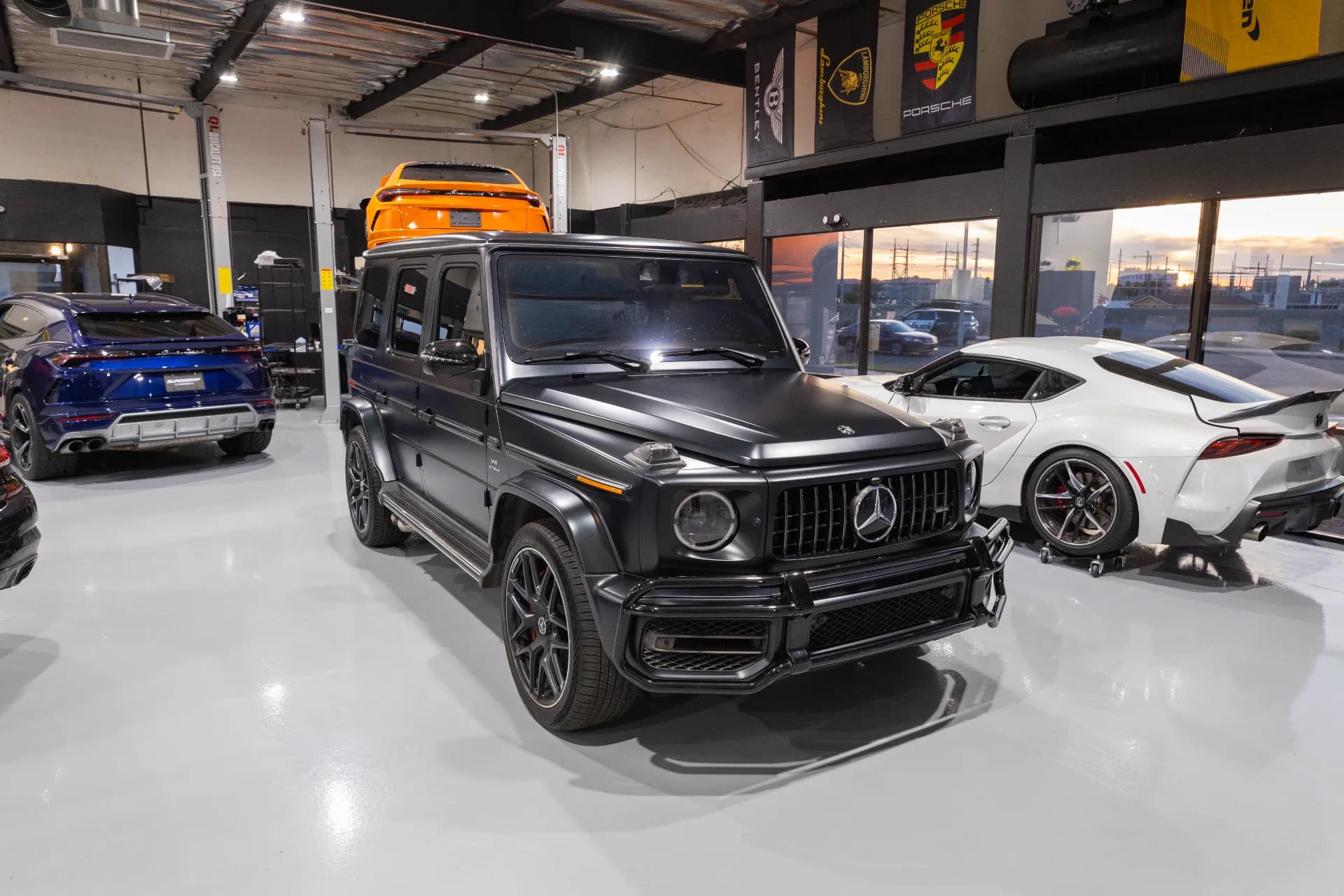 Mercedes-AMG G63 on the EuroComp Garage shop floor, Lamborghini Urus on the lift behind it
